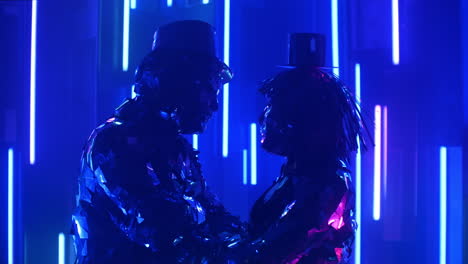 Two-dancers-a-man-and-a-woman-standing-opposite-each-other-shaking-in-time-to-the-music-synchronously-head-in-sparkling-mirrored-costumes-in-blue-violet-color-of-shimmering-neon.